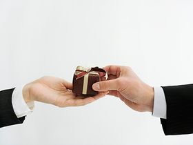 Zwei Hände im Bild, eine Hand überreicht der anderen ein kleines 