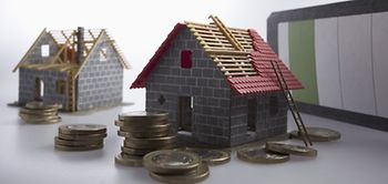 Zwei Hausmodelle mit teilweise fertiggestelltem Dach und Münzen