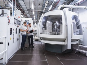 zwei junge Mitarbeiter kontrollieren Roboter in Fabrik