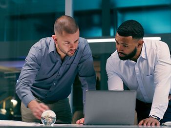 zwei Kollegen schauen auf den Laptop