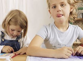 Zwei Maedchen sitzen am Tisch beim Malen