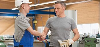 Zwei Männer, einer im Blaumann, schütteln sich die Hand