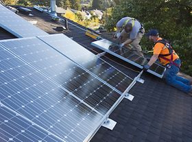 Zwei Männer in Schutzkleidung installieren Solarzellen auf Dach