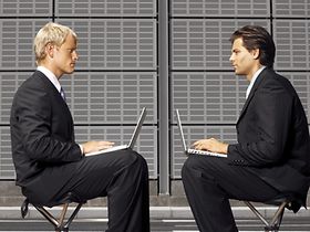 Zwei Männer mit Laptop sitzen sich gegenüber