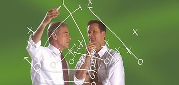 Zwei Männer zeichnen Linien vor grüner Wand