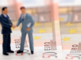 two figures of business men standing upon bank notes